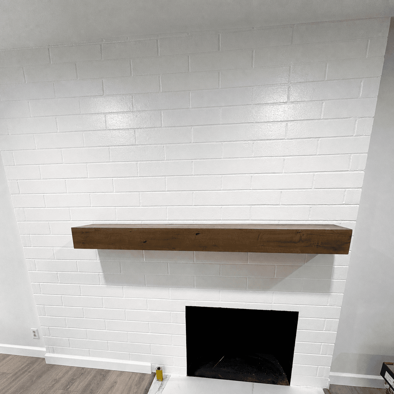 Interior remodel with painted-brick fireplace and floating wood mantel