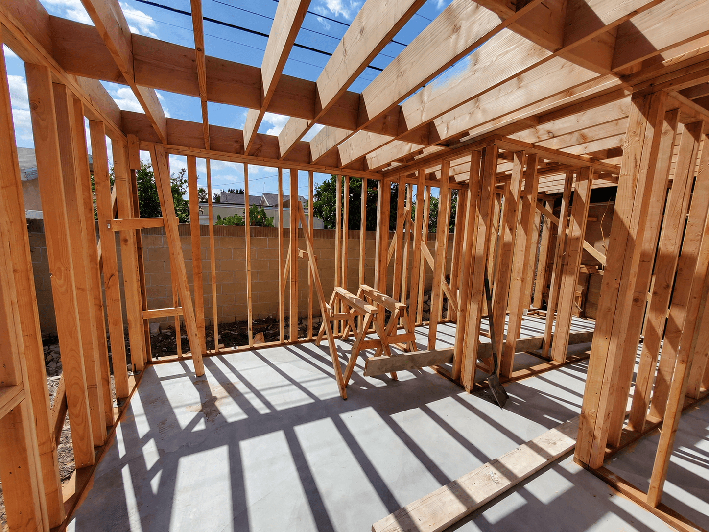 Wood-frame ADU interior with floor joists, roof rafters, and slab in place